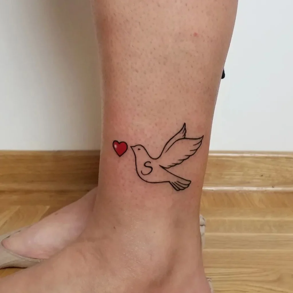 Tattoo of a dove with a heart on the shin for women