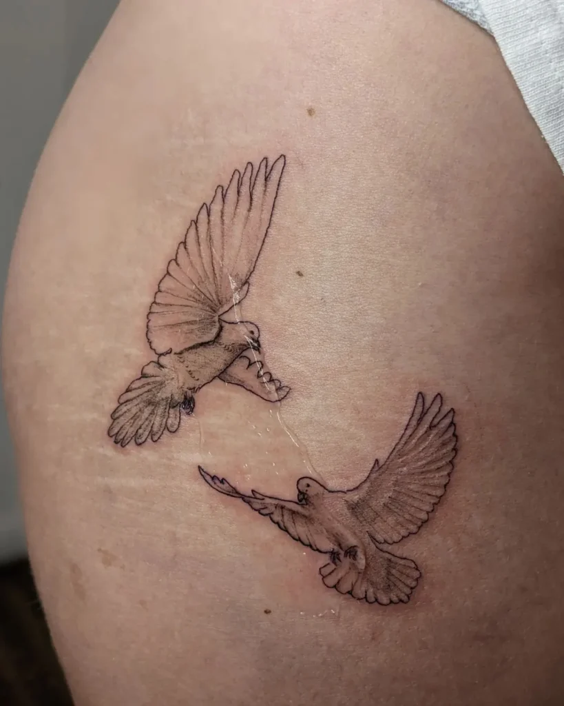 Tattoo of two doves on the thigh for women