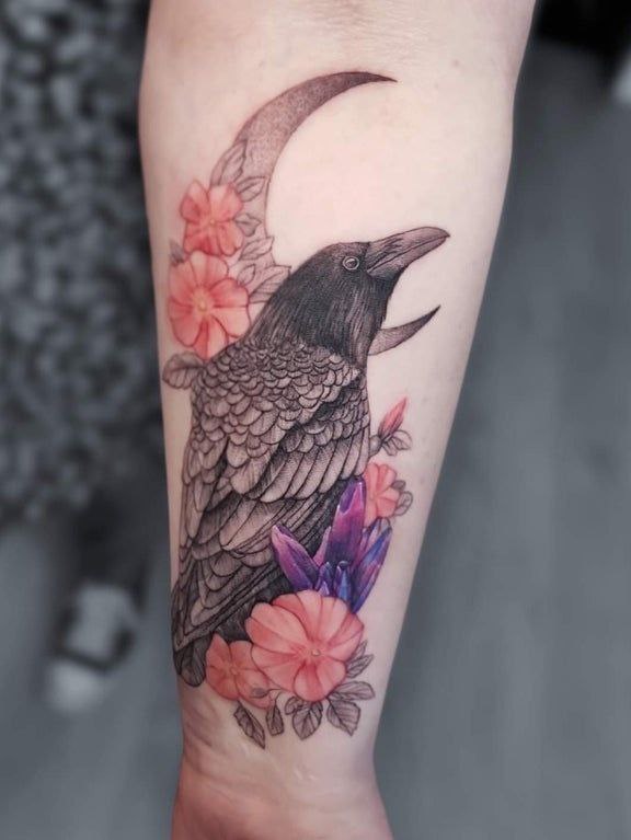 Tattoo of a raven with flowers on the forearm for women