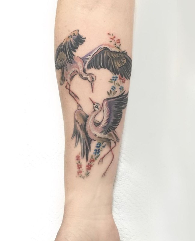 Color tattoo of two storks on the forearm for women