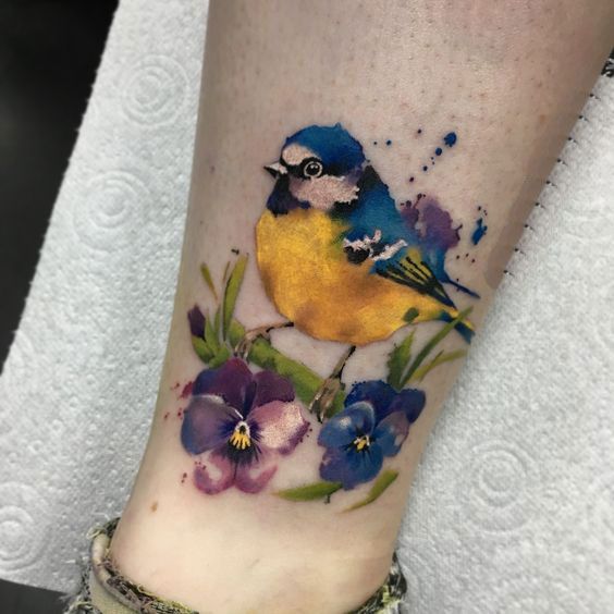 Color tattoo of a tit with flowers on the shin for women