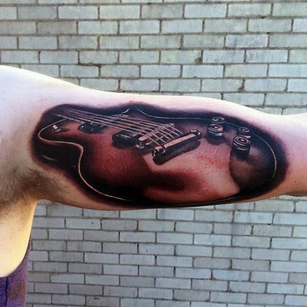 Colored guitar tattoo on the biceps for men