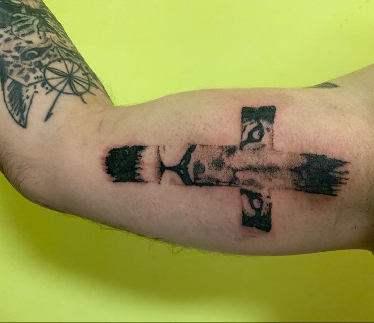 Large cross tattoo on the biceps for men