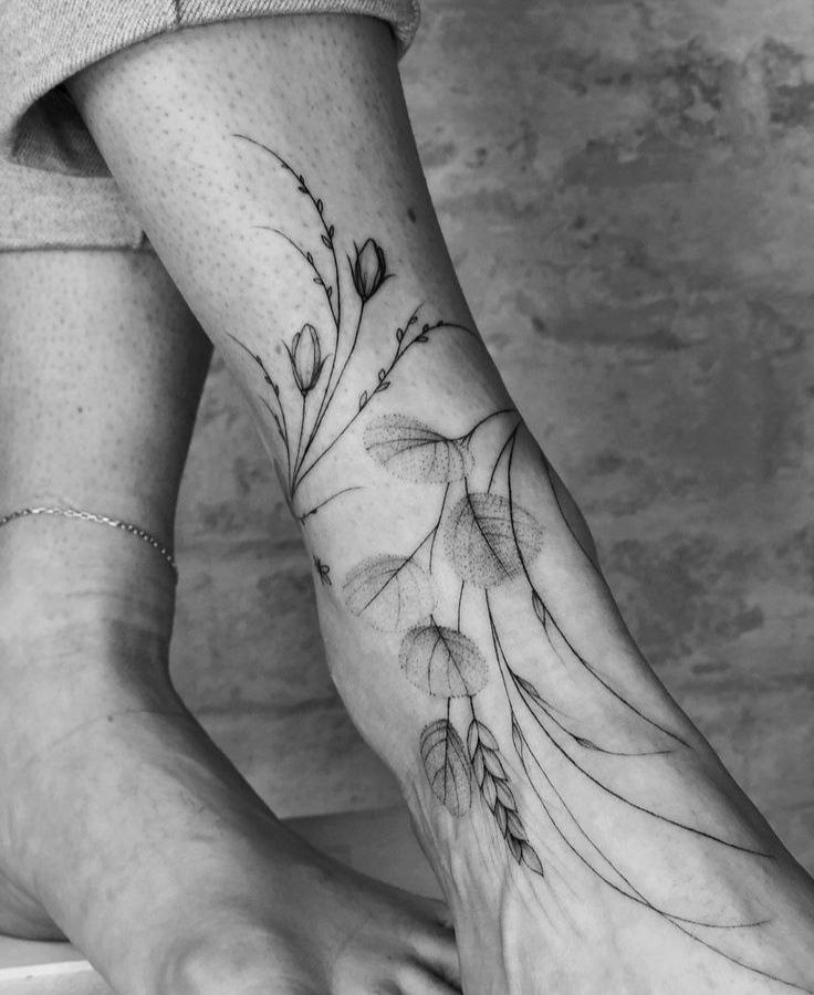 Large tattoo of leaves and flowers on the ankle for women