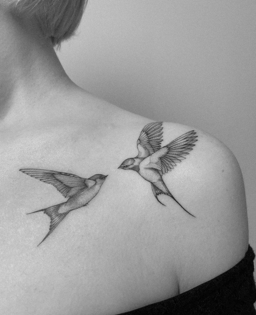 Large tattoo of two swallows on the collarbone for women