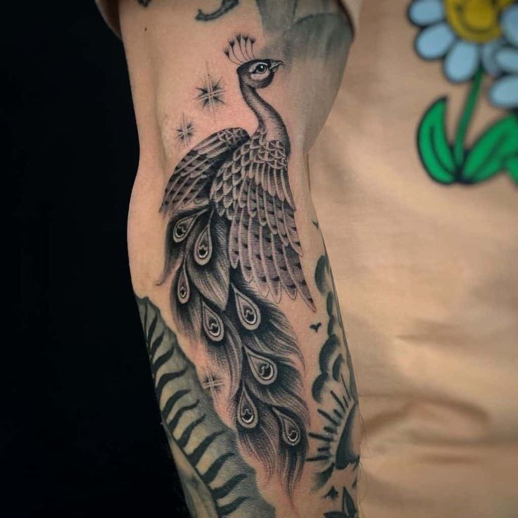 Large tattoo of a peacock on the forearm for men