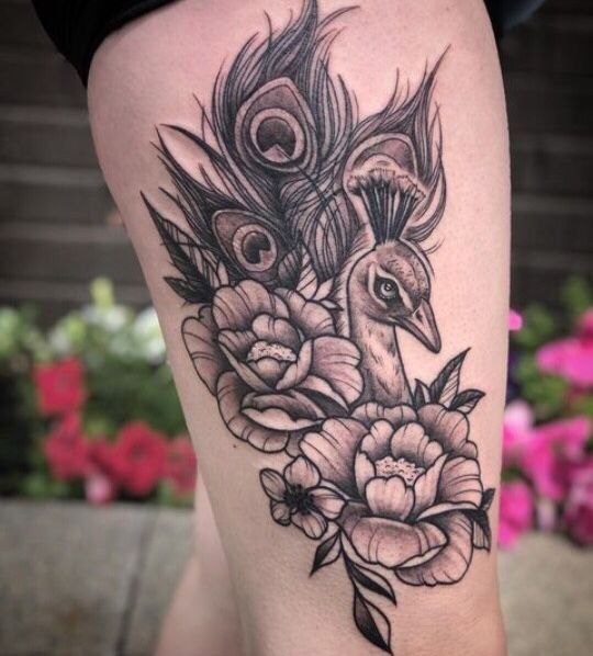 Large tattoo of a peacock and flowers on the thigh for women