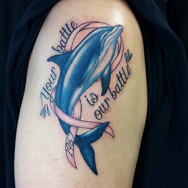 Large dolphin tattoo with inscription on the shoulder for men