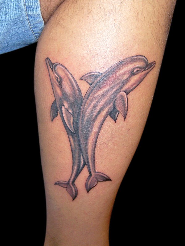 Large tattoo of two dolphins on the shoulder for women