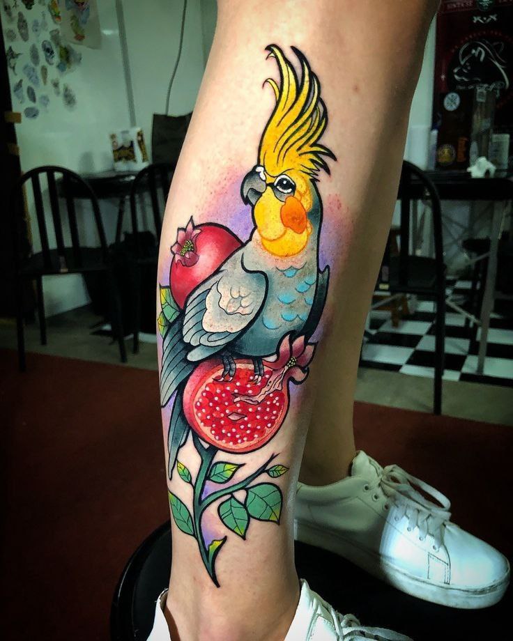 Colorful parrot tattoo with a pomegranate on the shin for women