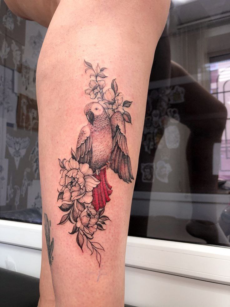 Parrot tattoo with flowers on the shin for women