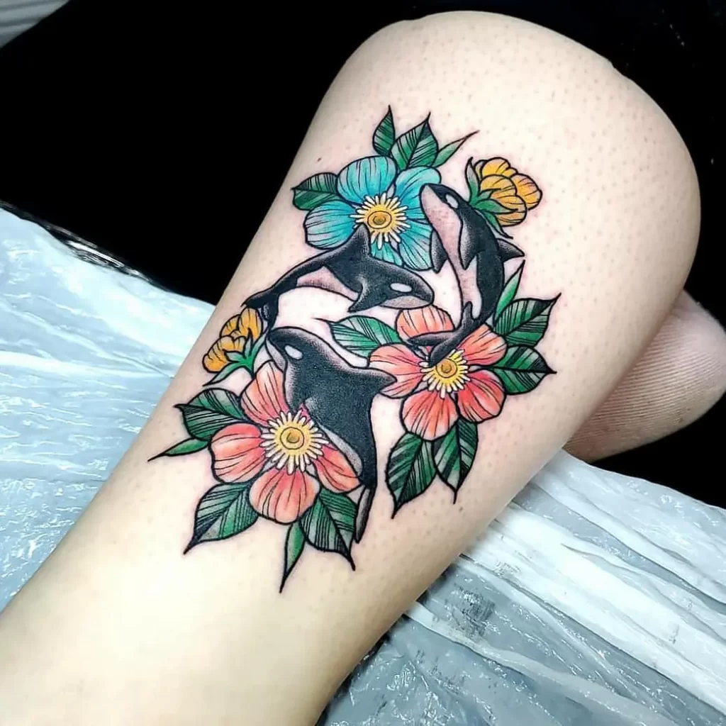 Colorful orca tattoo with flowers on the thigh for women