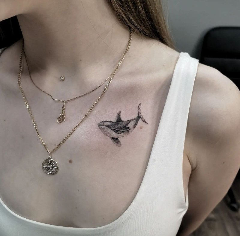 Small orca tattoo on the collarbone for women