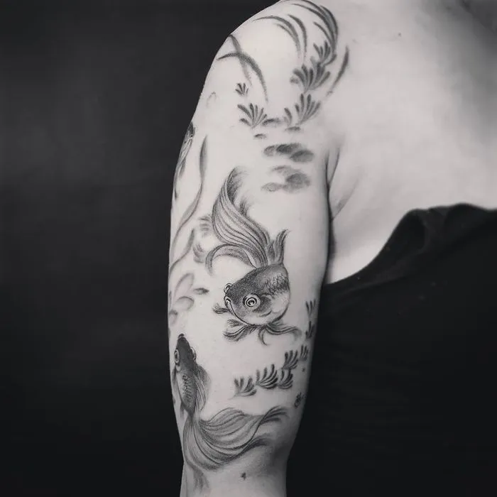 Tattoo of two goldfish on the shoulder for women