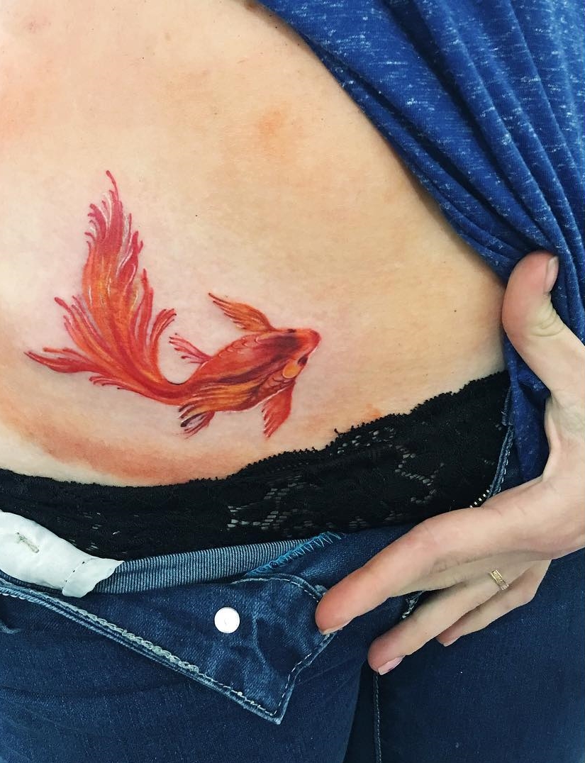 Colored goldfish tattoo on the stomach for women