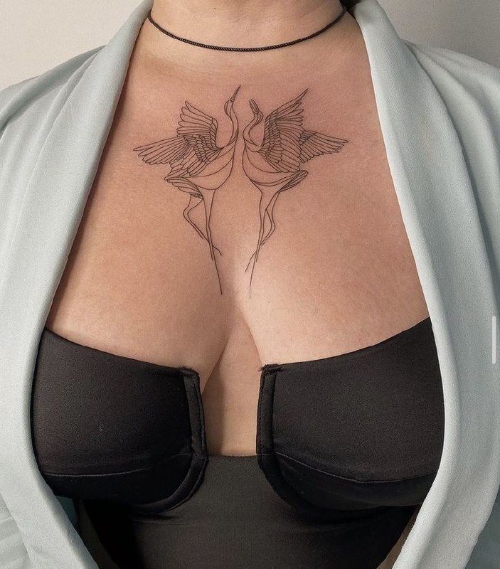 Tattoo of two storks on the chest for women