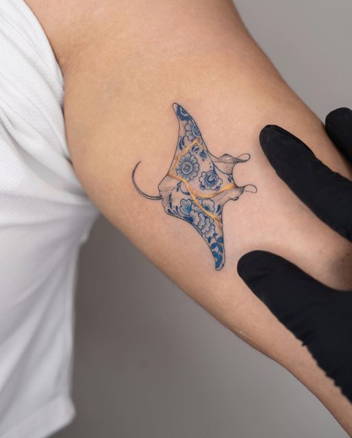 Colored stingray tattoo on the biceps for men