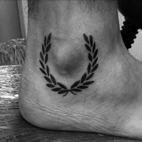 Tattoo of a sprig of leaves on an ankle for men