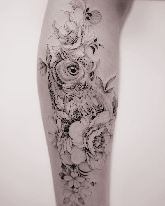 Large tattoo of an owl and flowers on the shin for women