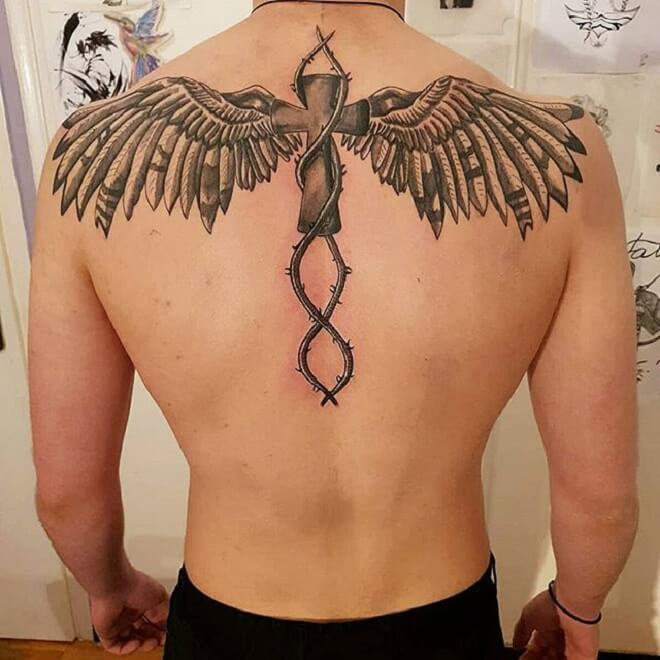 Tattoo of a cross and wings on the spine for men