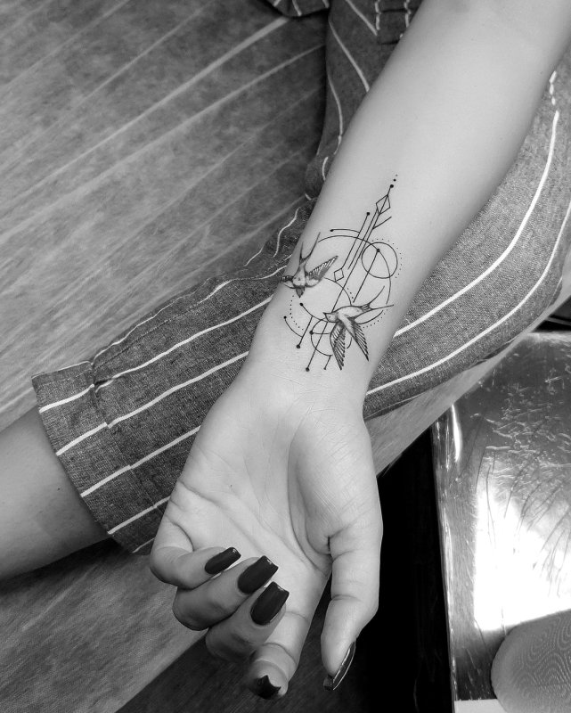 Tattoo of two swallows in graphic style on the wrist for women