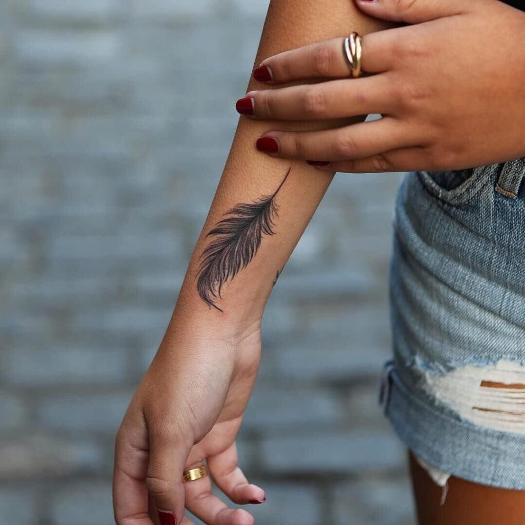 Tattoo of a feather on the arm for women