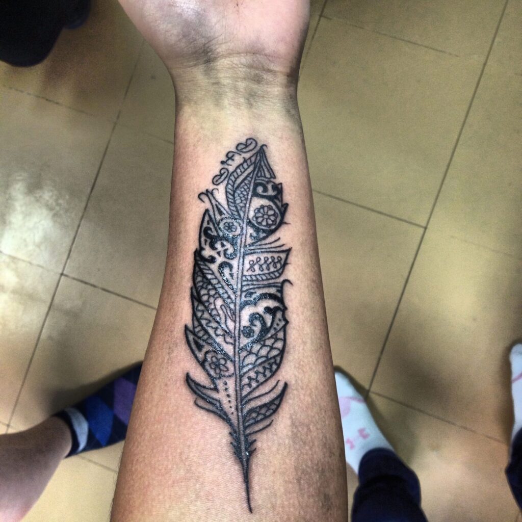 Tattoo of a feather on the forearm for men