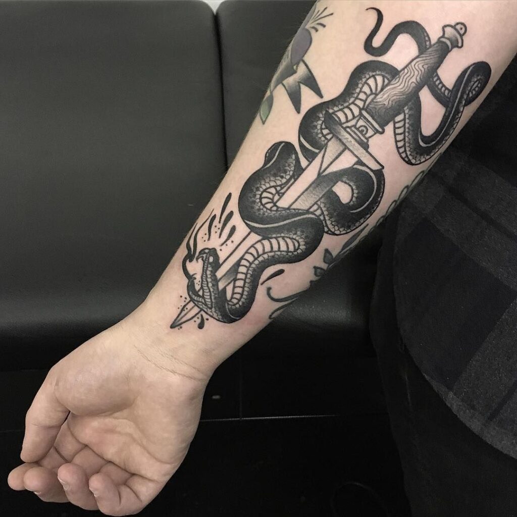 Large snake and dagger tattoo on the forearm for men