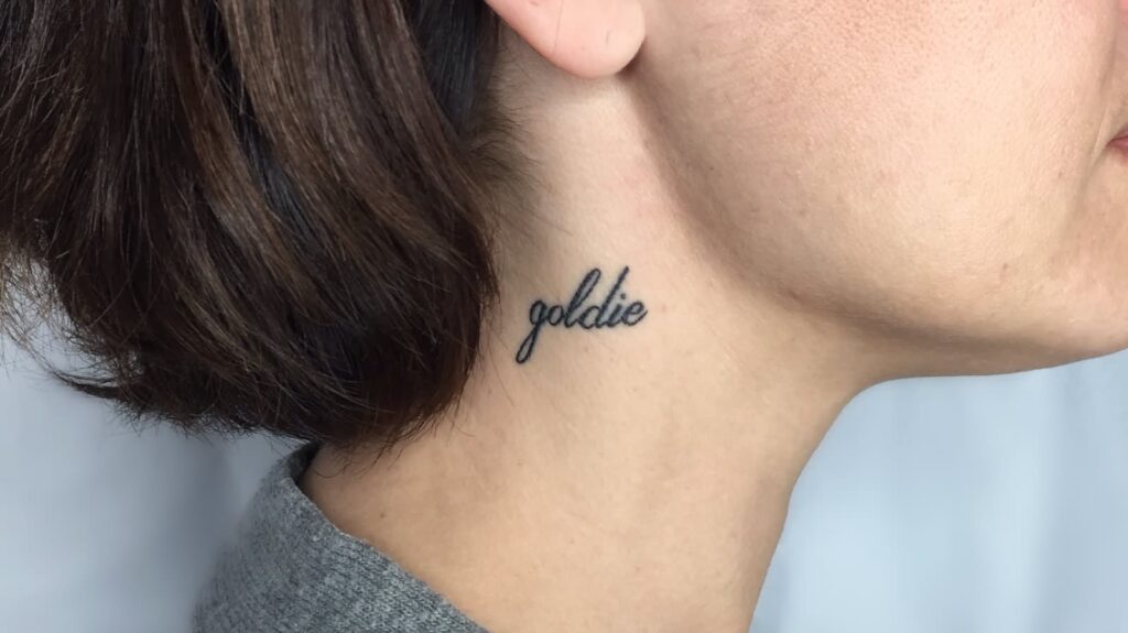 Tattoo with an inscription on the neck for women