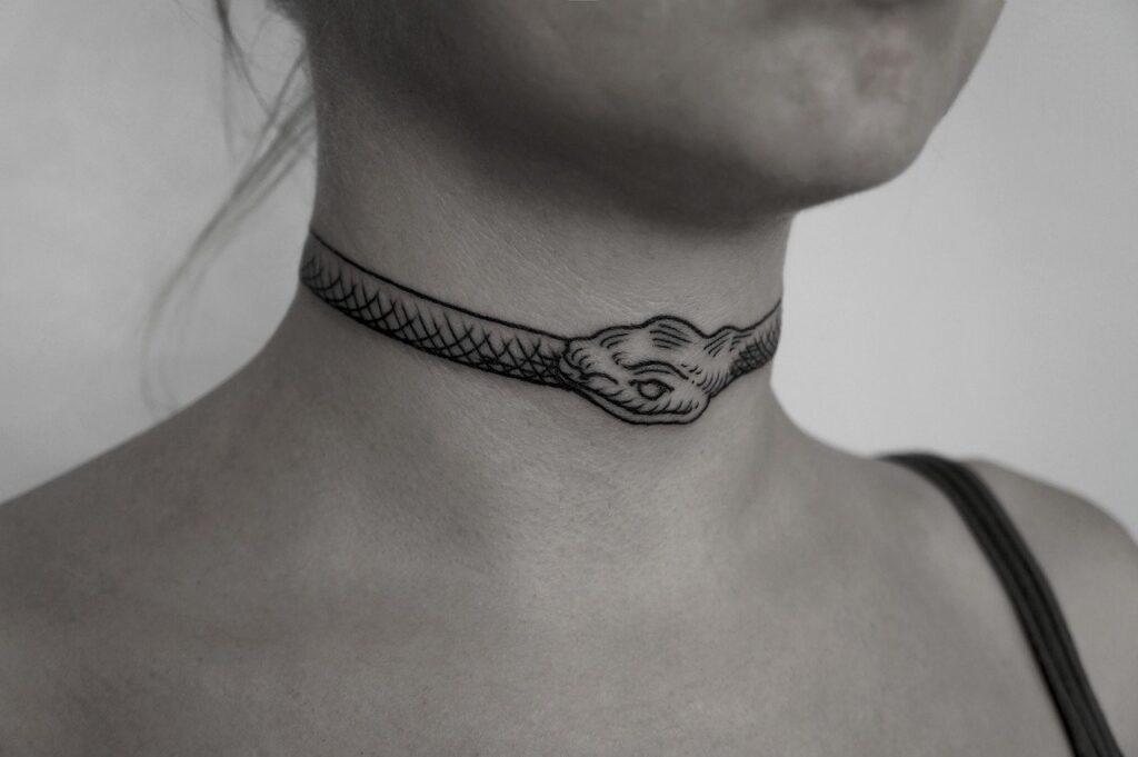 Uroboros tattoo on the neck for women