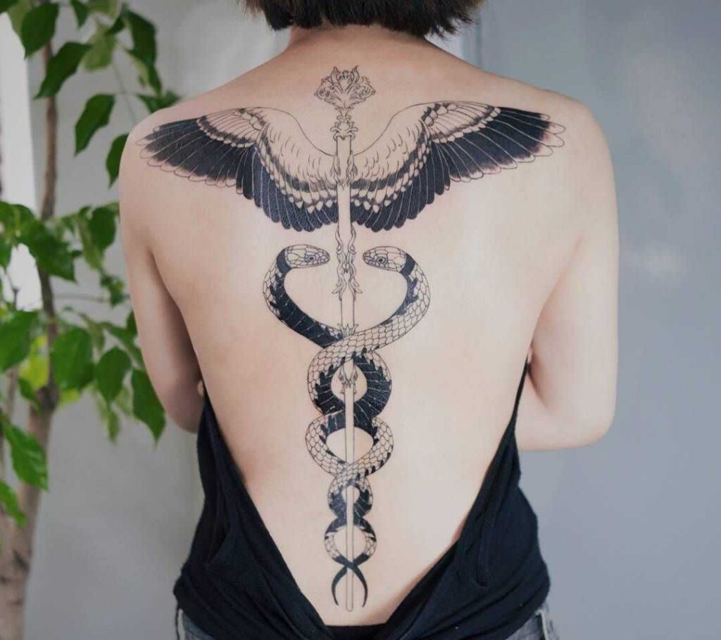 Large tattoo of two snakes on the back for women