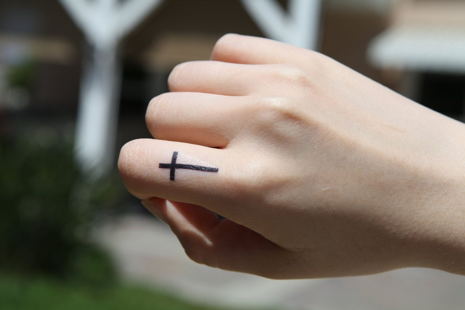 Cross tattoo on the finger for women