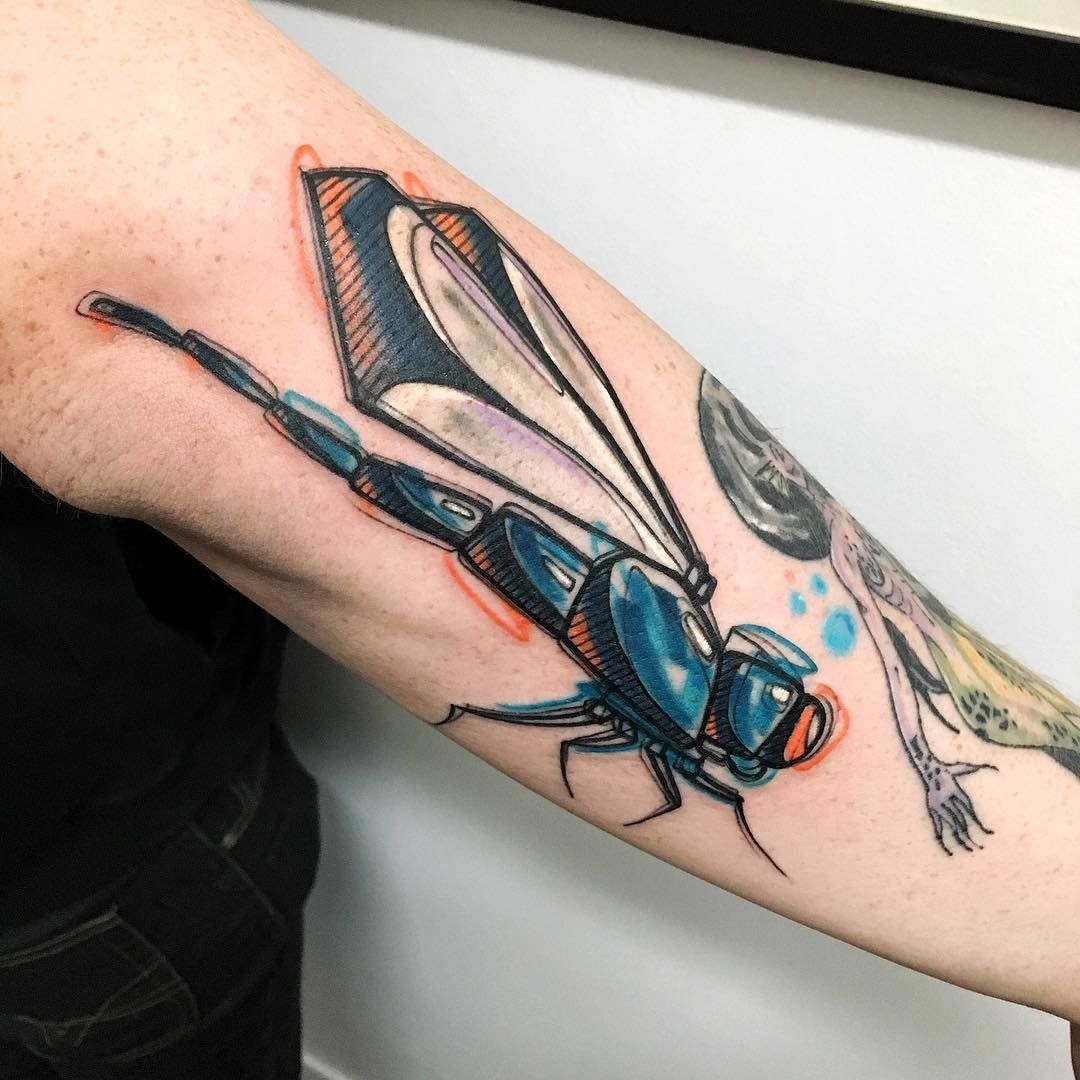 Color dragonfly tattoo in art-brut style on the arm for men