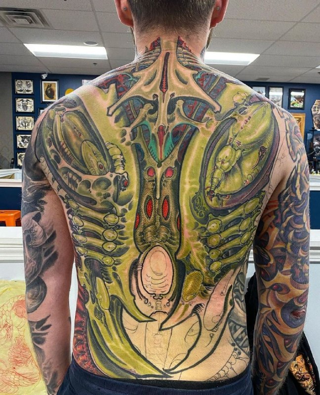 Colored tattoo in the style of biomechanics on the back for men