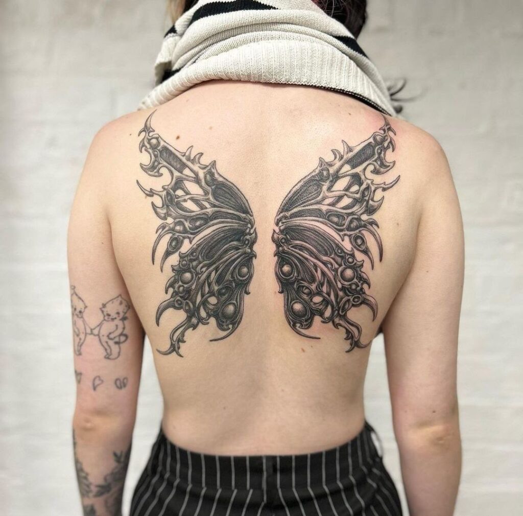 Biomechanics style tattoo on the back for women