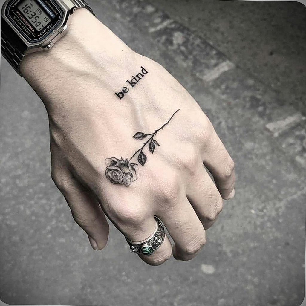 A small rose tattoo with an inscription on the hand for men