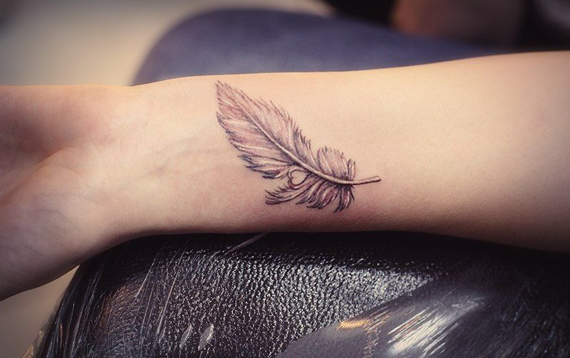 Tattoo of a feather on the wrist for men