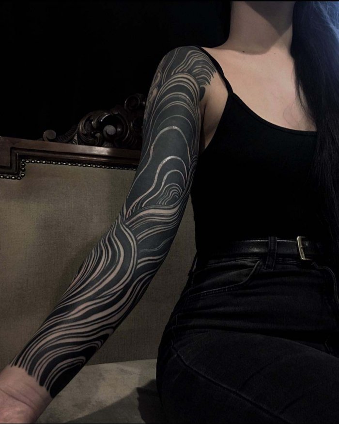 Blackwork style tattoo on the arm for women