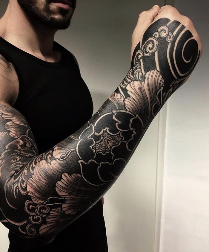 Large blackwork style flower tattoo on the arm for men