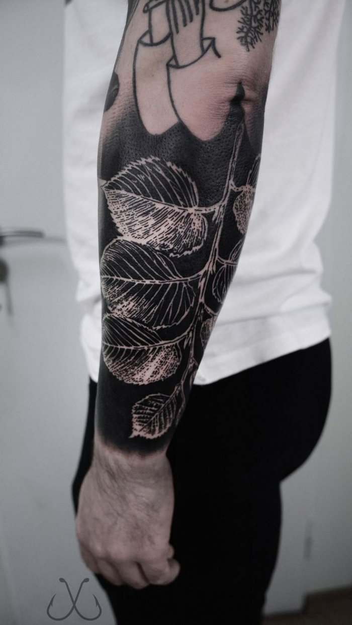 A large blacwork style leaf tattoo on the arm for women