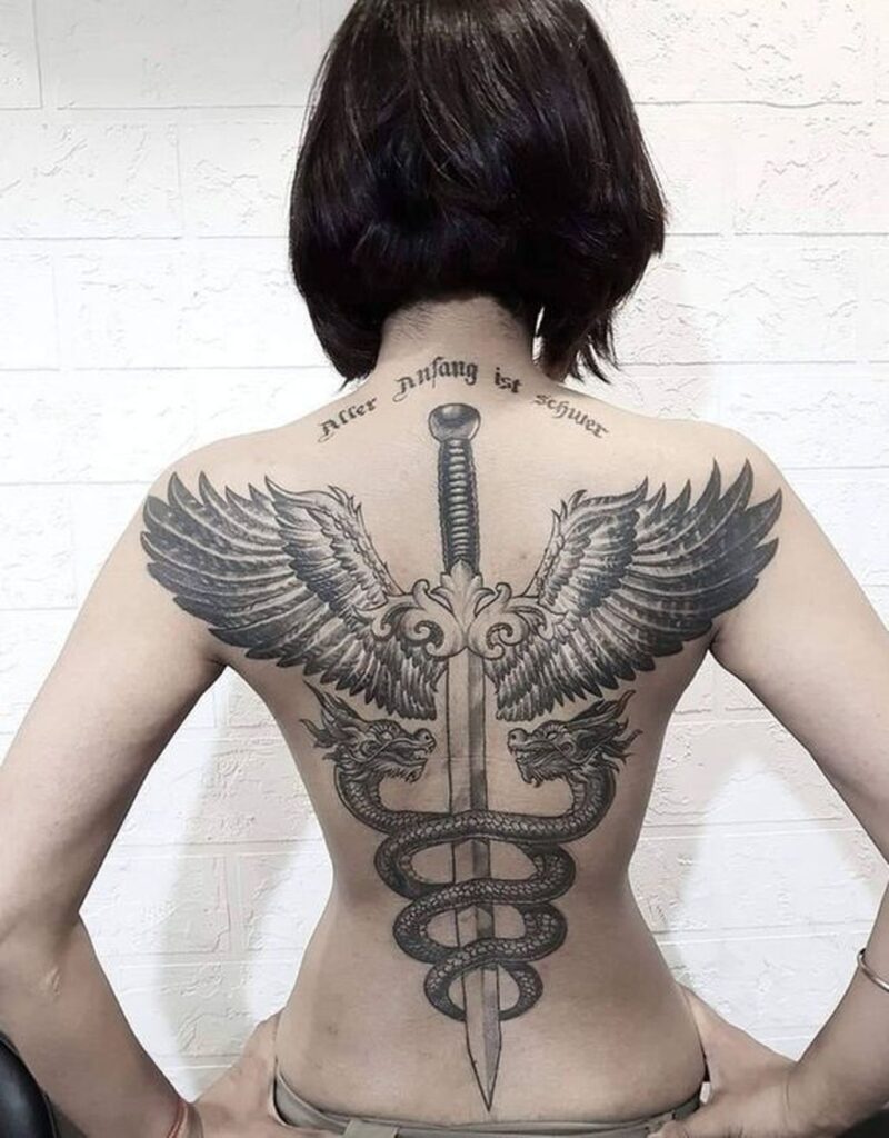 Large tattoo of wings and dagger on the back for women