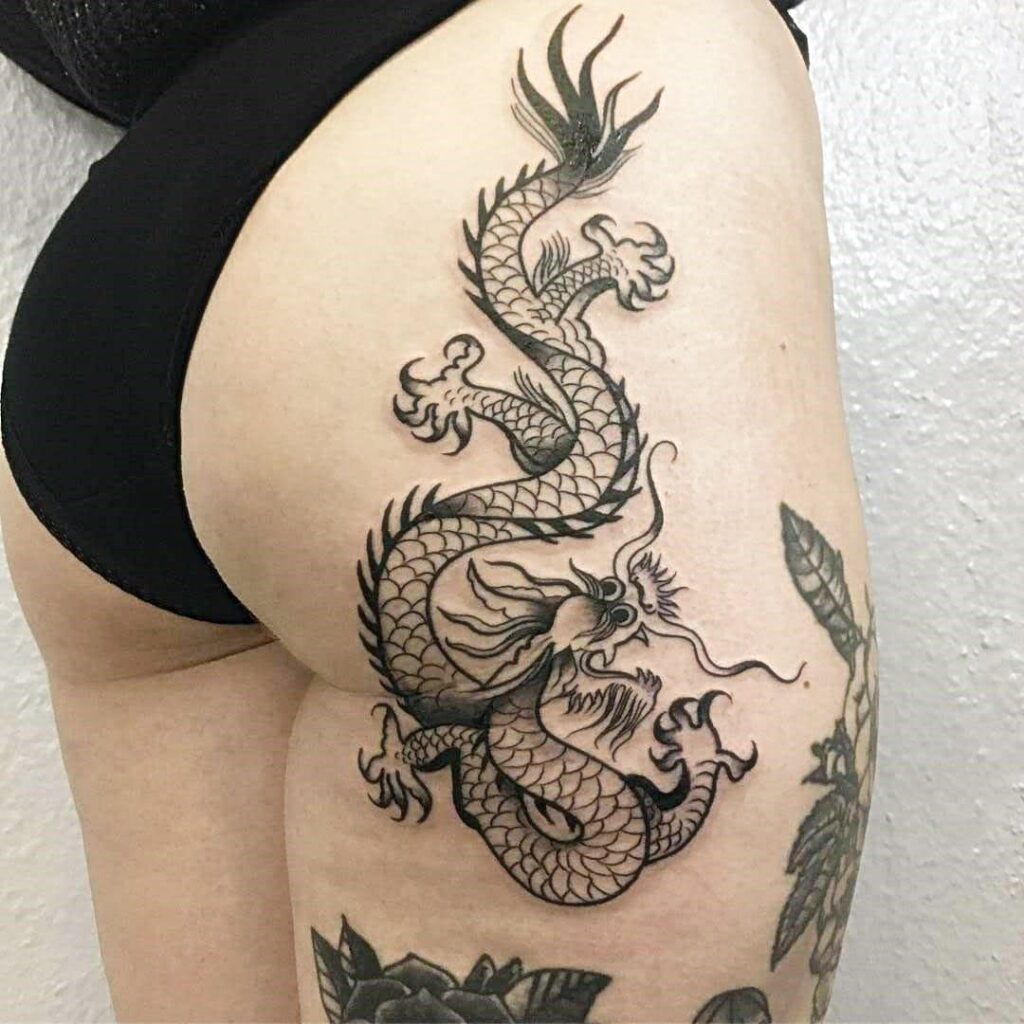 Large dragon tattoo on the thigh for women