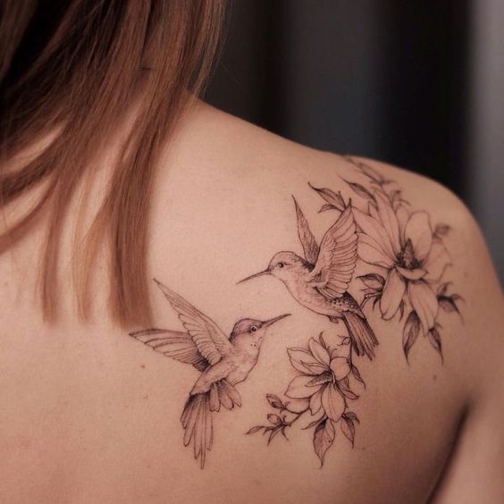 Large tattoo of two hummingbirds on the shoulder blade for women