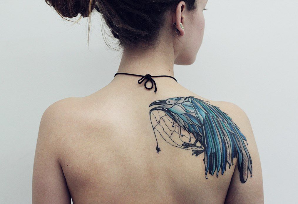 Colorful crow tattoo on the shoulder blade for women