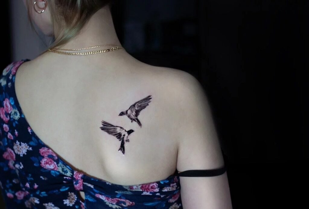 Tattoo of two birds on the shoulder blade for women