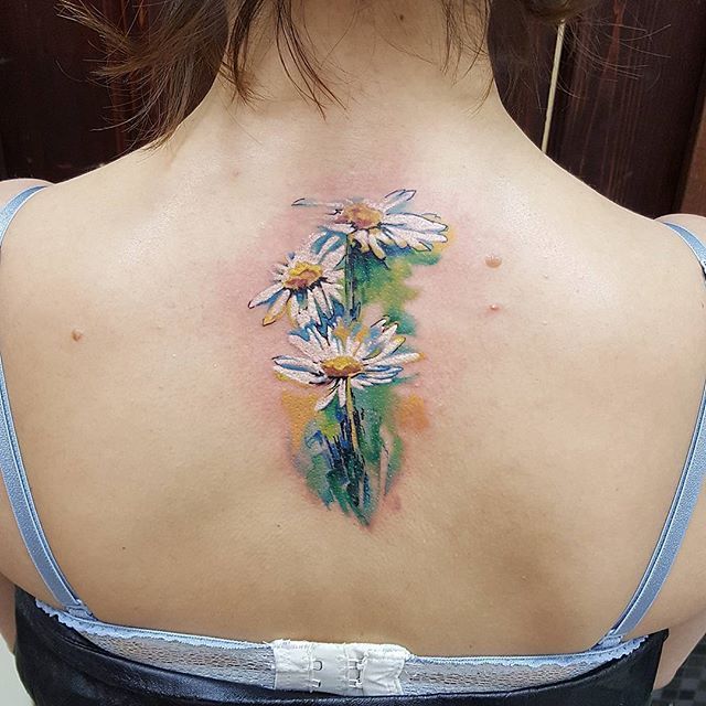 Colored daisies tattoo on the spine for women