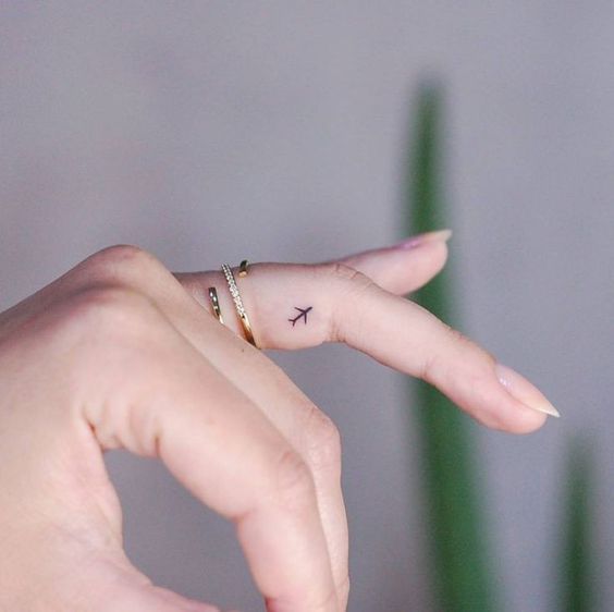 A small airplane tattoo on the finger for women