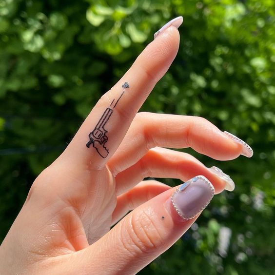 Tattoo of a gun on the finger for women