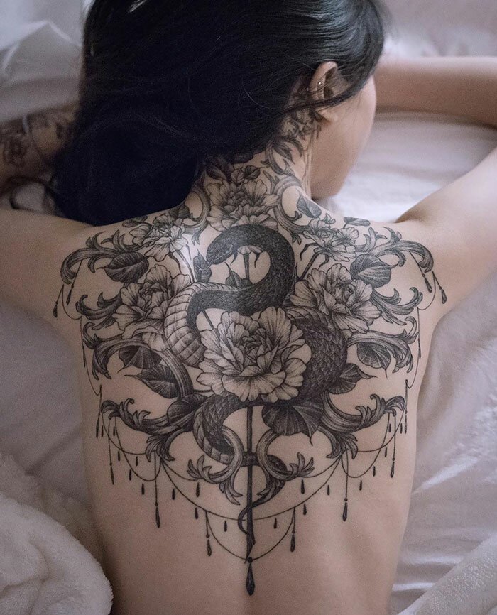 Large snake and flowers tattoo on the back for women