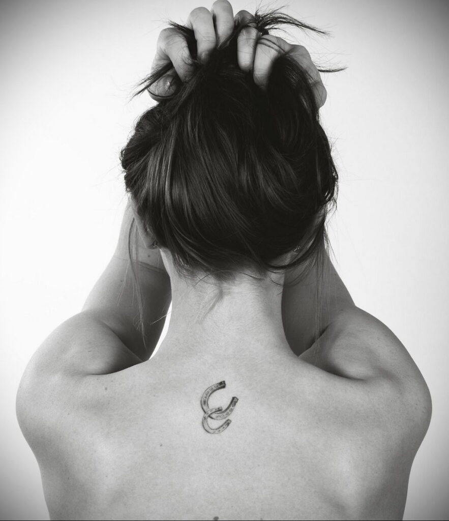 Tattoo of two horseshoes on the back for women